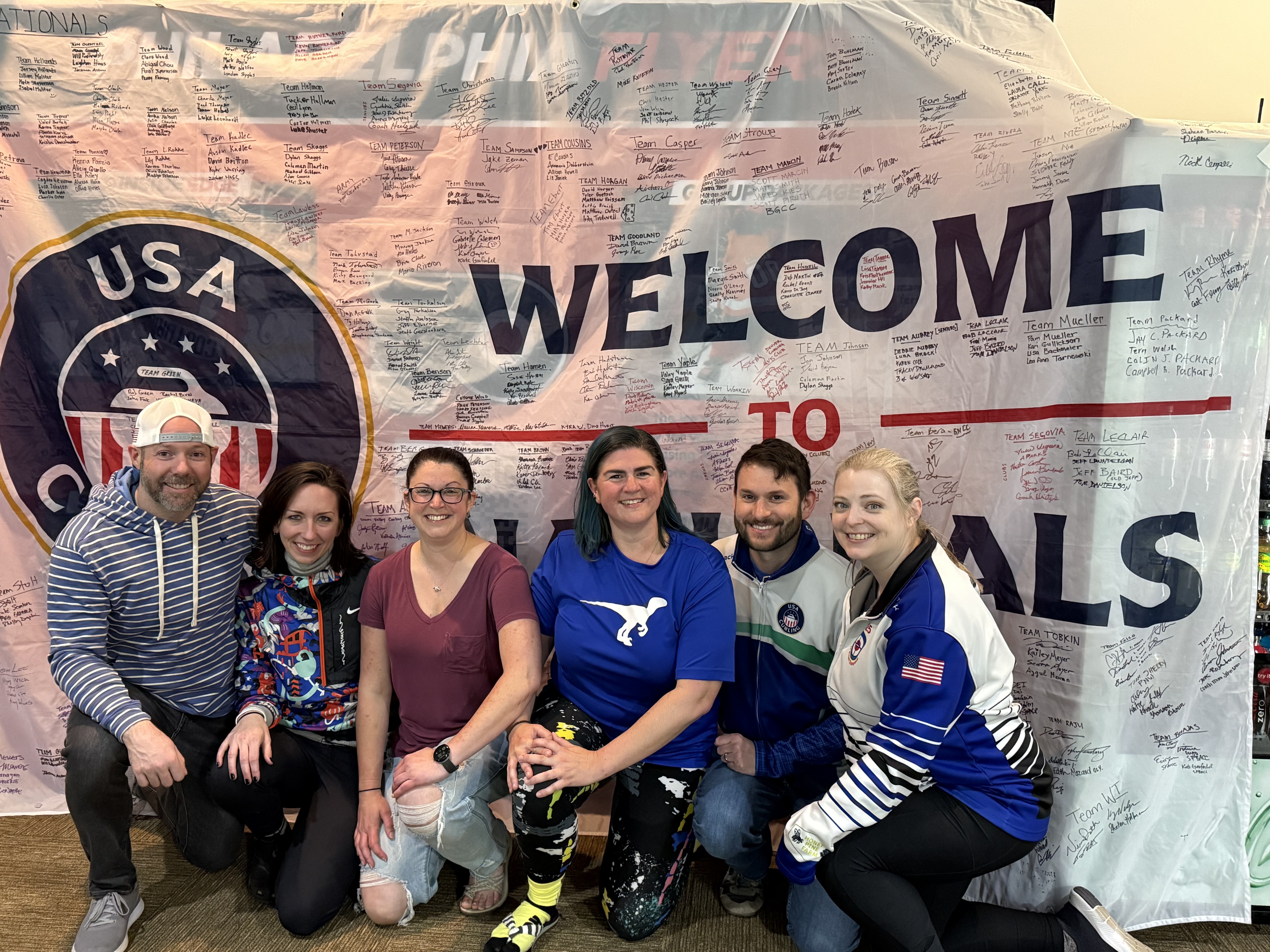 Image of JPCC members in front of USA Curling Nationals banner